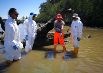PENGARAH Bahagian Keselamatan Sekuriti dan Alam Sekitar, Jabatan Laut Malaysia, Mohd. Fairoz Rozali (dua dari kanan) menunjukkan keadaan air laut yang semakin pulih akibat tumpahan sisa minyak di Pantai Cermin, Batu 10, Port Dickson.
