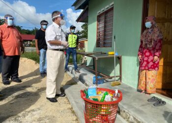 MENTERI Kesihatan, Datuk Seri Dr. Adham Baba menyampaikan bakul makanan kepada salah seorang penduduk Kampung Lukut, Kota Tinggi.