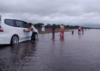 SEBUAH keluarga bermain air dan mencuci kereta di Jalan Bagan Serai-Changkat Lobak yang dinaik air di Bagan Serai semalam. - UTUSAN/WAT KAMAL ABAS