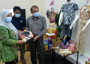 'AINU SHAM RAMLI (kiri) menunjukkan antara produk kraf dihasilkan kepada Kamruddin Domat selepas majlis penutup Program Pembangunan Kemahiran Komuniti (PPKK) Kraf Batik dan Jahitan di Pusat Kejiranan Presint 9, Putrajaya hari ini. - UTUSAN/AMREE AHMAD