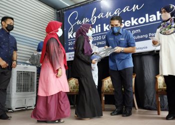 MOHD. Radzi Md. Jidin (dua dari kanan) menyampaikan sumbangan sambil diperhatikan Halimaton Shaadiah Saad (kanan) pada majlis sumbangan Kembali Ke Sekolah di Pusat Khidmat DUN Bukit Kayu Hitam, Napoh, Kubang Pasu hari ini.