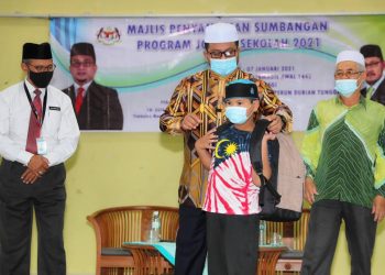 AHMAD Marzuk Shaary (tengah) menyampaikan beg sekolah kepada pelajar sambil diperhatikan Penasihat Agama kepada Ketua Menteri, Datuk Kamarudin Sidek (kiri) pada majlis penyampaian sumbangan program Jom Ke Sekolah 2021 di Durian Tunggal, Alor Gajah, Melaka. - UTUSAN/ RASUL AZLI SAMAD
