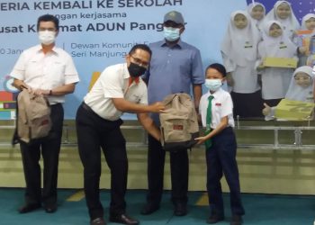 SEORANG pegawai pengurusan kanan MAHB menyampaikan sumbangan pada Program Ceria Kembali ke Sekolah #MyAirportCARES disaksikan Zambry Abd. Kadir (tengah) di Seri Manjung. - UTUSAN/SHAMSUL KAMAL AMARUDIN