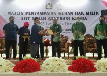RASMAN Ithnain (tiga dari kanan) menyampaikan geran hak milik lot tanah generasi kedua kepada salah seorang penerima di Felda Bukit Aping Barat, Kota Tinggi, Johor.