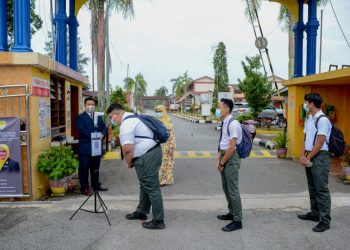SALIM Ab. Ghani (kiri) melihat pelajar tingkatan lima kohort 2020 di Sekolah Menengah Kebangsaan (SMK) Datuk Razali Ismail memeriksa suhu sebelum memasuki sekolah di Kuala Terengganu hari ini. - UTUSAN/PUQTRA HAIRRY ROSLI