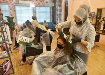 NOOR Hidayah Kamarulzaman (berdiri, kanan) mengunting rambut pelanggan  di Ammara Hair Salon, Taman Putra Utama, Kangar, Perlis, sebelum PKP, baru-baru ini.– UTUSAN/NAZLINA NADZARI