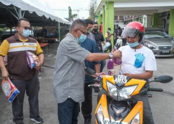 HANAFIAH Mat (dua dari kiri) mengagihkan bantuan kepada pengusaha kedai gunting rambut di sekitar Chukai di Pejabat Dewan Undangan Negeri (DUN) Chukai di Kemaman.