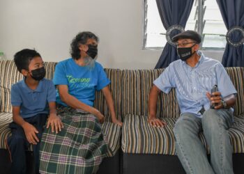 ROSOL Wahid (kanan) menjadikan pelajar pintar, Muhammad Mu’az Zhofri Mohamad Yong sebagai anak angkatnya semasa lawatan di Kampung Losong Haji Mat Shafie di Kuala Terengganu,  hari ini. - UTUSAN/PUQTRA HAIRRY ROSLI