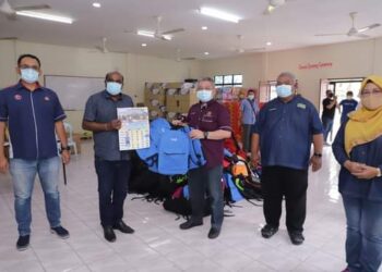 ADHAM Baba (tengah) menyerahkan sumbangan beg sekolah di Balai Raya Taman Kota Jaya, Kota Tinggi, Johor.
