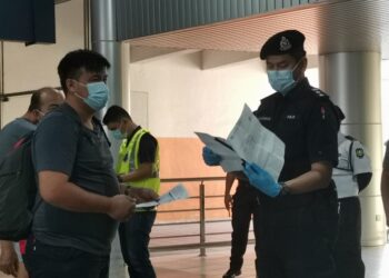 SHARIMAN Ashari memeriksa permit kebenaran rentas daerah penumpang yang menaiki feri ke Kuala Kedah di Terminal Feri Penumpang Kuah, Langkawi hari ini.- UTUSAN/NUR AMALINA AZMAN