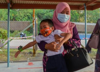 RAGAM murid Tahun 1, Sekolah Kebangsaan (SK) Bukit Sawa yang terpaksa didukung guru bertugas pada hari pertama persekolahan secara bersemuka di Marang hari ini. - UTUSAN/PUQTRA HAIRRY ROSLI