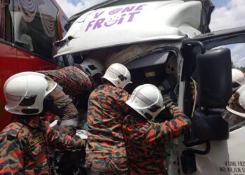 ANGGOTA Bomba dan Penyelamat mengeluarkan  pemandu lori yang tersepit dalam kemalangan jalan raya dengan sebuah bas ekspres di Jalan Parit Seraya, Benut, Pontian. - GAMBAR IHSAN BOMBA