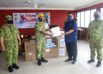 JEFRIDIN Atan (dua  dari kanan) menyerahkan PPE  kepada Fariman Ismail di Tanjung Piai Resort, Pontian.