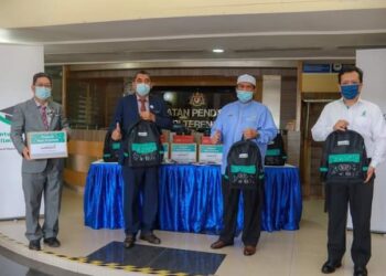 SATIFUL Bahri Mamat (dua kanan) memegang beg sekolah yang disumbangkan Yayasan Petronas menerusi program Kembali Ke Sekolah di Jabatan Pendidikan negeri di Kuala Terengganu.