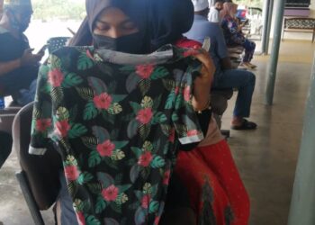 SYARIFAH Ramli setia memegang baju terakhir dipakai suaminya sebelum kejadian lemas di Sungai Petuang, Tasik Kenyir ketika ditemui di Unit Forensik Hospital Hulu Terengganu di Hulu Terengganu, hari ini. -UTUSAN/NOOR HAYATI MAMAT