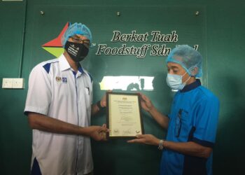 ROSOL Wahid menyerahkan sijil logo Buatan Malaysia kepada Syarikat Berkat Tuah Foodstuff. - UTUSAN/DIYANATUL ATIQAH ZAKARYA