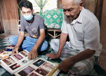 HASHIM Rejab (kanan) membelek foto lama ditemani Ah Hua di rumahnya di Sungai Dua, Butterworth, Pulau Pinang, semalam.