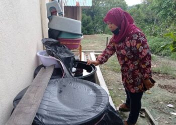 ROZANA Mohamad menunjukkan bekalan air yang ditadah dalam tong sebagai kegunaan ketika berdepan masalah catuan air di beberapa kawasan di Kota Tinggi, Johor. -UTUSAN/MASTURAH SURADI