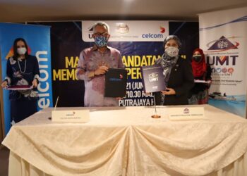 MOHAMAD IDHAM Nawawi (kiri) dan Nor Aeni Mokhtar menunjukkan memorandum persefahaman yang ditandatangani mereka sebagai mewakili Celcom dan UMT di Hotel The Everly Putrajaya malam tadi. - UTUSAN/AMREE AHMAD