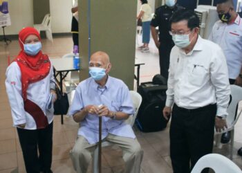 CHOW Kon Yeow dan Dr. Asmayani Khalib menyantuni seorang warga emas yang menerima suntikan vaksin Covid-19 dalam fasa kedua di Kompleks Masyarakat Penyayang, Georgetown, Pulau Pinang. - UTUSAN/MUHAMMAD FIRDAUS AMRAN