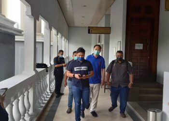 CHUNG Chee Yang (berbaju biru) diiringi pegawai polis hadir di Mahkamah Majistret Kuala Lumpur bagi menghadapi pertuduhan mencederakan dua pengawal peribadinya - UTUSAN/NORLIZAH ABAS