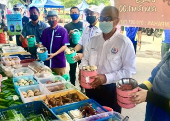 AZIZAN Sulaiman (kanan) bersama Shamsuharizal Basir membeli juadah makanan menggunakan mangkuk tingkat sempena program penyerahan mangkuk tingkat dan kempen hargai makanan, elak pembaziran sempena bulan Ramadan di bazar Ramadan Arau, Perlis semalam.- UTUSAN/MOHD. HAFIZ ABD. MUTALIB