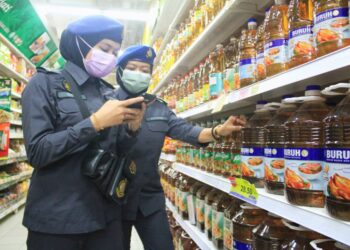 DUA pegawai penguat kuasa PPDNHEP menjalankan pemeriksaan harga minyak masak botol dalam operasi pemantauan harga di sebuah pasar raya di Bayan Lepas, Pulau Pinang. -UTUSAN/MUHAMMAD FIRDAUS AMRAN