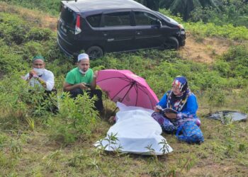 ROSMAWATI Jali membaca Yasin untuk suaminya yang meninggal dunia di Kilometer 325.7, Lebuhraya Pantai Timur 2 (LPT2) berhampiran Kertih di Kemaman, Terengganu, hari ini.