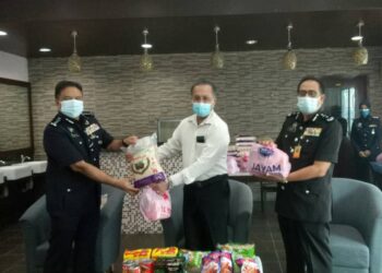 SAHABUDIN Abd. Manan (kiri) menerima sumbangan barangan keperluan asas untuk anggota IPK daripada Jagdeep Singh Deo di IPK negeri, Georgetown, Pulau Pinang.