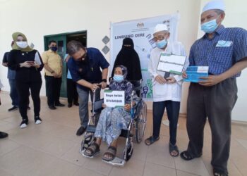 ABDUL Latif Ahmad (dua kiri) bertanya sesuatu kepada ibunya, Hasnah Roslan sambil diperhatikan bapanya, Ahmad Syukor selepas mengambil vaksin di PPV Dewan Jubli Intan Mersing di Johor. - UTUSAN/MASTURAH SURADI