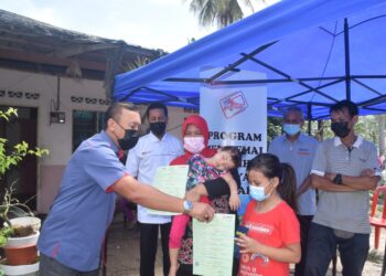 RUSLIN Jusoh (kiri) menyerahkan sijil kelahiran daftar lewat kepada Nur Iffika Dahlia Rusli dan adiknya, Nur Irine Delisha di Kampung Gong Balai, Mercang di Marang.