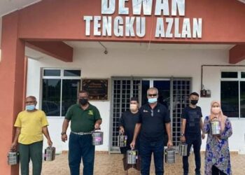 NAZRI Ngah (depan tiga dari kiri) bersama sukarelawan UMNO Jerantut dan ahli JKKK bersedia dengan mangkuk tingkat berisi makanan untuk disumbangkan kepada keluarga yang kurang berkemampuan di PPMS Kampung Bukit Rang, di Jerantut, Pahang. - UTUSAN/HARIS FADILAH AHMAD