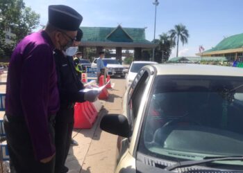 AHMAD Shukri Mat Akhir bersama seorang anggota polis memeriksa surat kebenaran merentas daerah daripada seorang pemandu di Plaza Tol Alor Setar Utara, Alor Setar, hari ini. - UTUSAN/NUR ANATI JUHARI