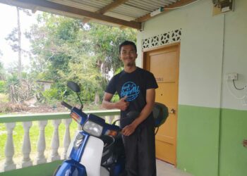 MUHAMMAD Yasir Mohd. Said bersama motosikalnya yang berjaya ditemukan semula selepas 30 minit memuat naik status berkenaan kehilangan kenderaan itu di Felda Pasak, Kota Tinggi, Johor. - UTUSAN/MASTURAH SURADI