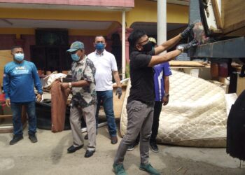 NORHIZAM Hassan Baktee (kanan) membuang barang yang rosak akibat banjir ke dalam lori sambil disaksikan Shadan Othman (tiga dari kanan) pada Program Pembersihan Pasca Banjir MPHTJ di Pulau Nibong, Pengkalan Batu, Melaka. - UTUSAN/MUHAMMAD SHAHIZAM TAZALI