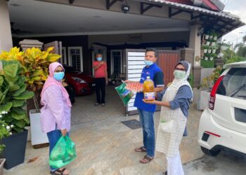 SHAHRIN Muharram (dua dari kanan) dibantu tiga pekerjanya menyerahkan pelbagai barangan makanan kepada penduduk Taman Terendak Permai, Sungai Udang, Melaka yang menjalani kuarantin selepas 24 penduduk positif Covid-19. - UTUSAN/AMRAN MULUP