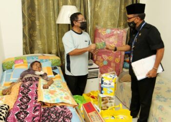 UNGKU Sulaiman Ungku Aziz (tengah) menerima sumbangan daripada Nasir Ishak (kanan) bagi membantu meringankan beban menjaga Zaleha Hamid yang terlantar diserang angin ahmar di kediaman mereka di PPR Uda Utama di Taman Uda Utama, Johor Bahru. -UTUSAN/BAAZLAN IBRAHIM