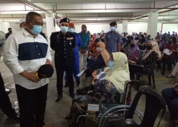 MUHAMMAD Sanusi Md. Nor (kiri) beramah mesra dengan salah seorang penerima vaksin di PPV Dewan Kenangan, MPSPK di Sungai Petani, hari ini. - UTUSAN/NUR SYAZWANA MANSOR