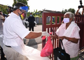 AMIRUDIN (kiri) memberikan bantuan makanan yang diberikan kepada penduduk di tiga buah taman di daerah Sabak Bernam, Selangor yang dikenakan arahan PKPD sehingga 12 Jun hadapan.