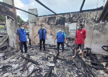 MUHAMMAD Nur Rasyid Judin (kanan) menceritakan kejadian kebakaran tesebut kepada Ghazali Abas (kiri) yang melawat kediaman tersebut di Felda Air Tawar 1, Kota Tinggi, Johor. -UTUSAN/MASTURAH SURADI