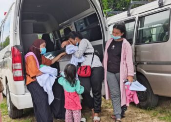 AWALAH (kiri) dan anak-anaknya meluangkan saat-saat terakhir bersama arwah Bibi di Taman Perkuburan Orang-orang Islam Kampung Contoh, Petagas, Sabah hari ini. -UTUSAN/SURAIDAH ROSLAN