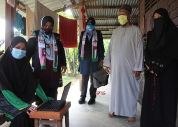 SITI Haidah Hazrul (kiri) mencuba komputer riba yang diterimanya sambil diperhatikan oleh bapanya (dua dari kanan) dan Zaiton Othman (kiri) di Kampung Seberang Baru Hampar, Rembau. - UTUSAN/NOR AINNA HAMZAH