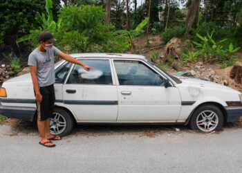 SEORANG penduduk menunjukkan kesan semburan cat pada sebuah kereta lama di Rumah Pangsa Senawang, Fasa 2, Taman Seri Mawar, Senawang, Seremban. - UTUSAN/MUHAMMAD IZZAT TERMIZIE