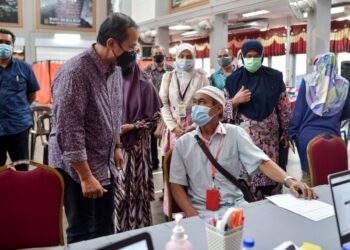 AHMAD Samsuri Mokhtar beramah mesra dengan seorang penerima vaksin di pusat pemberi vaksin (PPV) Kuala Berang di Hulu Terengganu. - UTUSAN/PUQTRA HAIRRY ROSLI