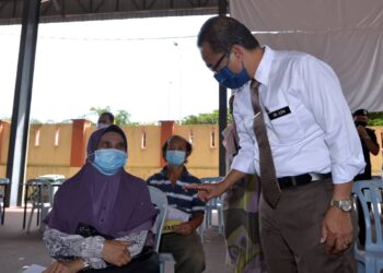 NOOR Azmi Ghazali (kanan) beramah mesra dengan seorang penerima vaksin Covid-19 ketika melawat PPV Dewan Merdeka, Tapah. - UTUSAN/ZULFACHRI ZULKIFLI