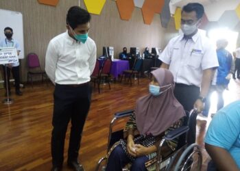 SAZZLI Kasim (kiri) beramah mesra dengan salah seorang penerima vaksin di PPV IPT UiTM Kampus Puncak Alam, Kuala Selangor. -  UTUSAN/MOHAMAD NAUFAL MOHAMAD IDRIS