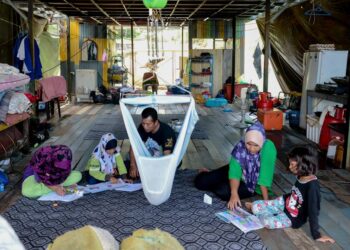 NOR Farhana Yusop dan suami, Shamsuddin Khalid mengajar anak-anak mereka mengulang kaji pelajaran di rumah bot di Tasik Kenyir, Hulu Terengganu. - UTUSAN/PUQTRA HAIRRY ROSLI