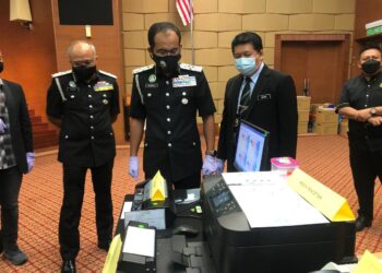 KHAIRUL Dzaimee Daud (tengah) melihat sebahagian peralatan yang dirampas Jabatan Imigresen untuk aktiviti pemalsuan dokumen ketika mengadakan sidang akhbar di Putrajaya. - UTUSAN/SUBKHI SUDARJI