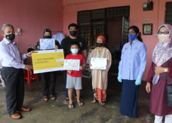 FUAD Alias (kanan) menyerahkan bayaran faedah Perkeso kepada Muhammad Haidir Rodzi (tiga dari kiri) yang kematian ibu dan bapa akibat Covid-19 di Bandar Sunggala, Port Dickson. - UTUSAN/NOR AINNA HAMZAH