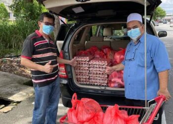 KAMARUL Rizduan Mohd. Zain (kanan) ketika menguruskan barang makanan harian yang akan diedarkan kepada keluarga yang dikuarantin susulan positif Covid-19 di Taman Pinggiran Senawang, Seremban hari ini.-UTUSAN/NOR AINNA HAMZAH.